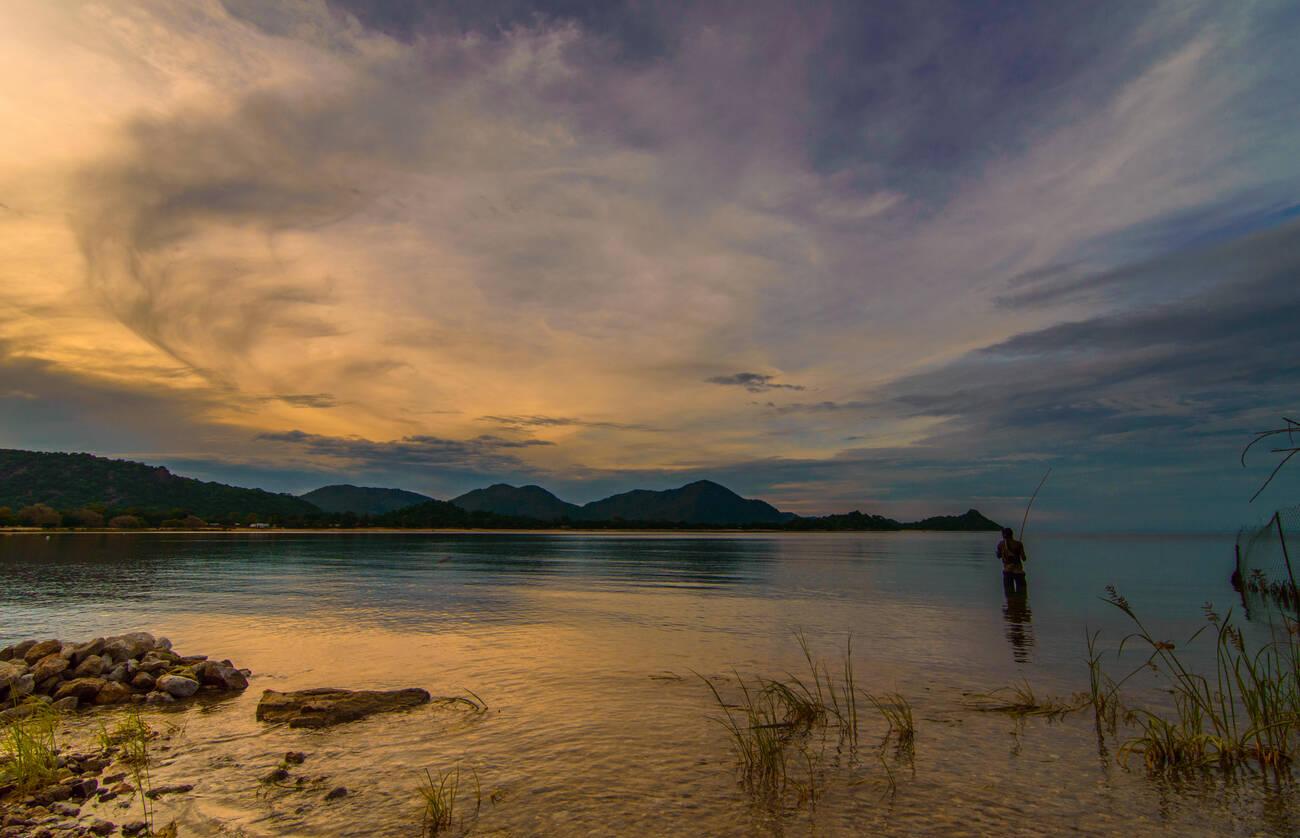 Fishermen stands in lake Malawi fishing with a rod Fishermen stands in lake Malawi fishing with a rod
