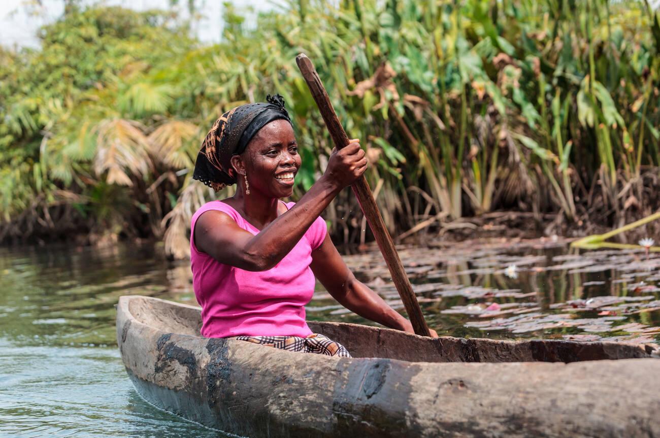 Africa, Liberia, Monrovia. Woman rowing traditional pirogue down Du River.