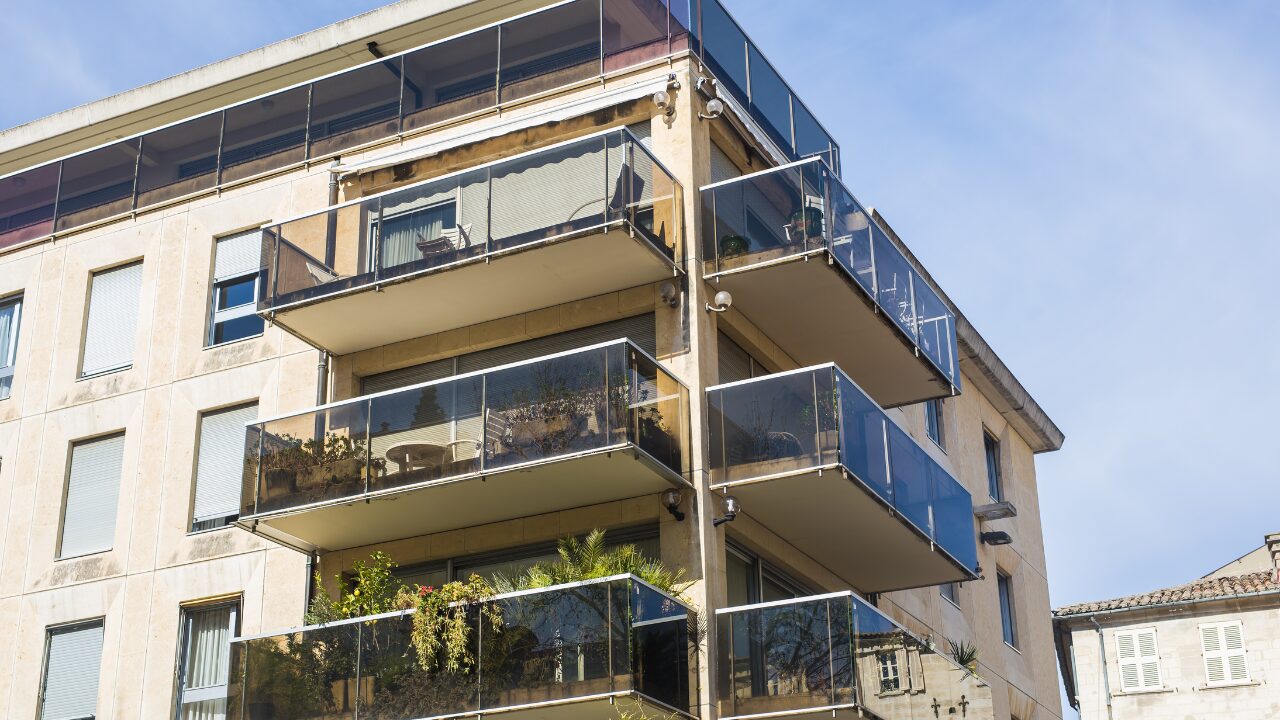  Modern commercial property with balconies and large windows on a sunny street 
