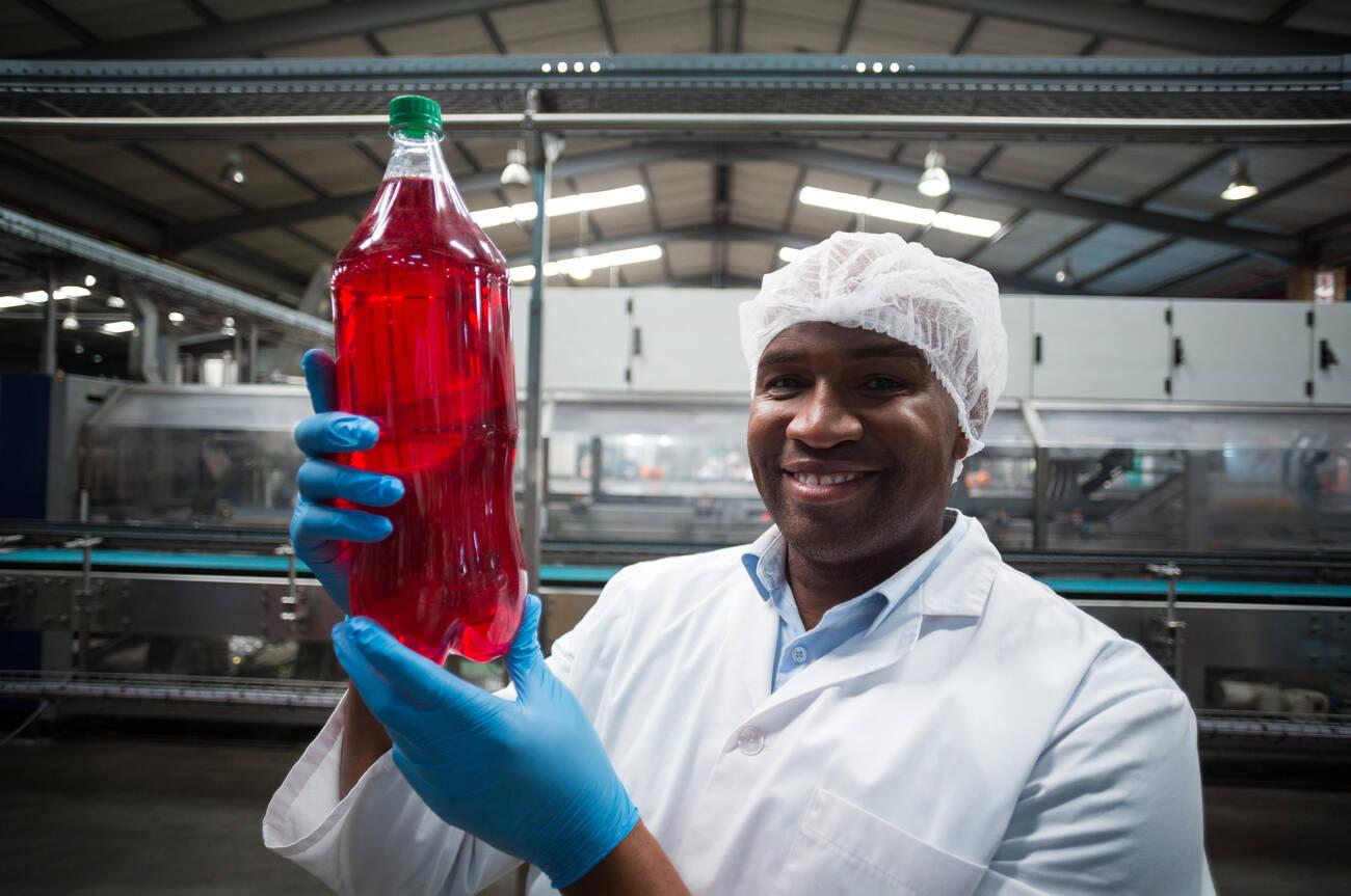 Portrait of factory engineer holding a bottle of juice in factory